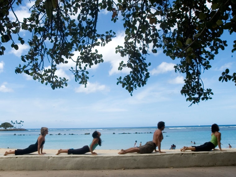 Participants stretch together in an \"upward facing dog\" pose during a \"guerilla yoga\" practice session alongside Ala Moana Beach in Honolulu, Hawaii.