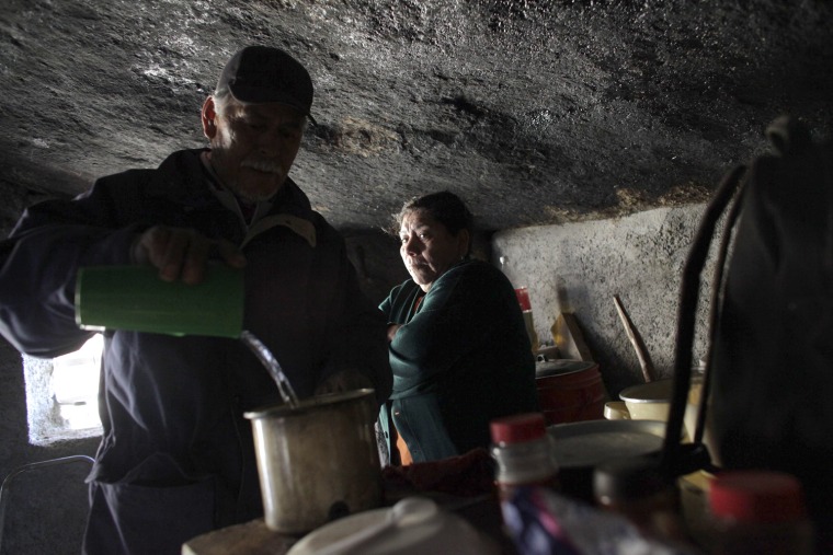 Santa Martha de la Cruz Villarreal stands nearby as her husband Benito Hernandez pours hot water into a cup at their home.