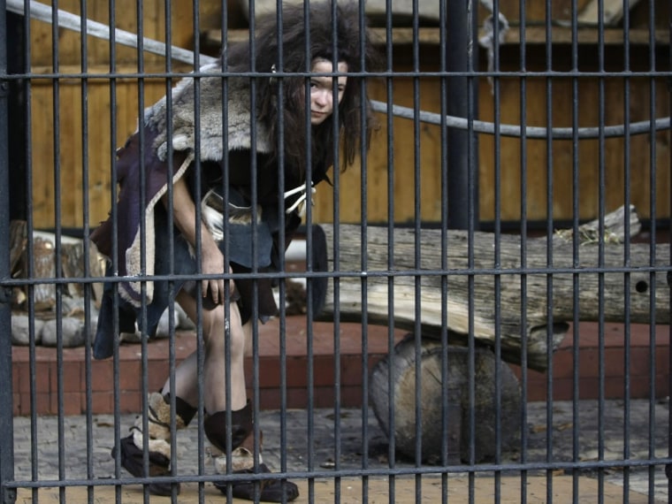 A volunteer dressed as a Neanderthal woman walks inside a cage at the Warsaw Zoo in Poland. Volunteers agreed to dress like Neanderthals and spend hours locked up in cages in an effort to educate the public that apes should be treated with respect. So how would neo-Neanderthals be treated?