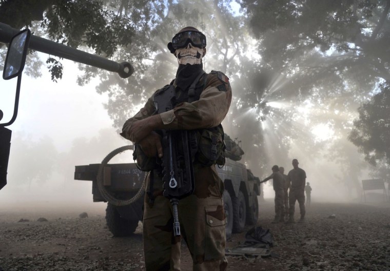A French soldier wearing a skeleton mask stands next to a tank in a street in Niono, Mali.