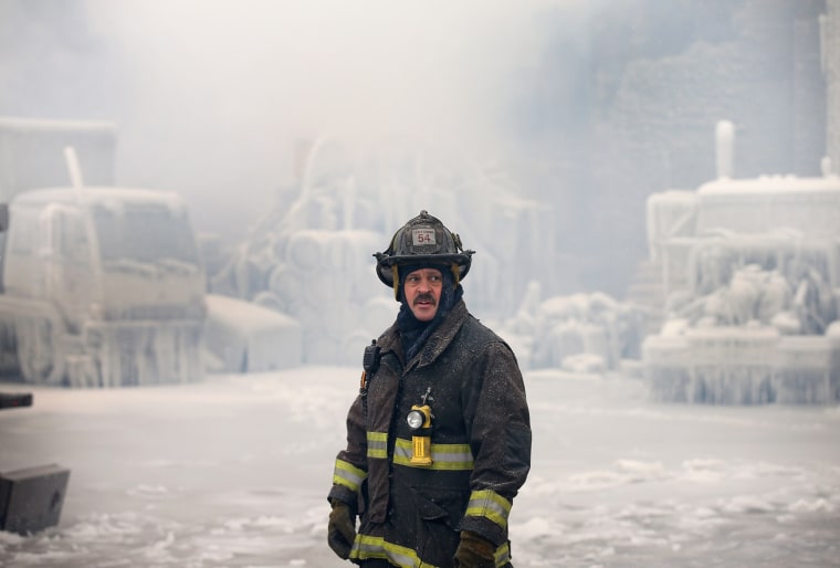 A firefighter helps to extinguish a massive blaze at a vacant warehouse on Jan. 23 in Chicago, Ill. More than 200 firefighters battled a five-alarm fire as temperatures were in the single digits.