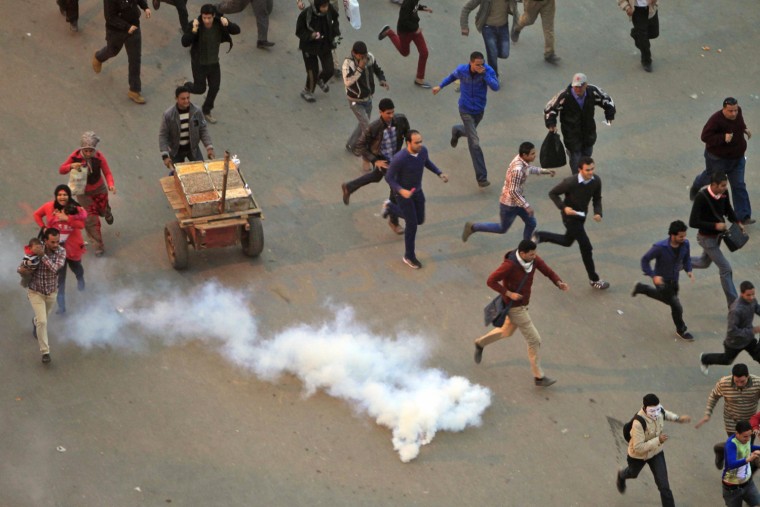 Protesters flee from tear gas fired by riot police during clashes after protesters removed a concrete barrier near Tahrir Square in Cairo on Jan. 24.