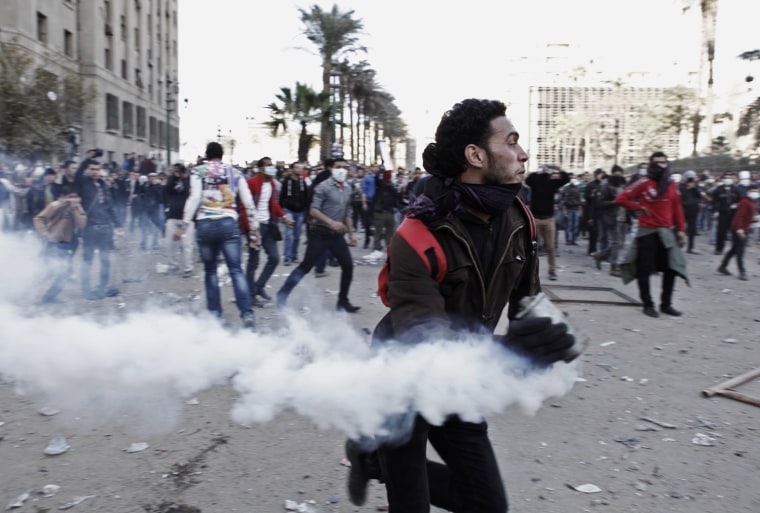 An Egyptian protester runs with a live tear gas canister during clashes with riot police in Tahrir Square on Jan. 25, in Cairo, Egypt. Thousands of protesters converged on the capital's iconic Tahrir Square on Friday to mark the second anniversary of the overthrow of former President Hosni Mubarak's regime.