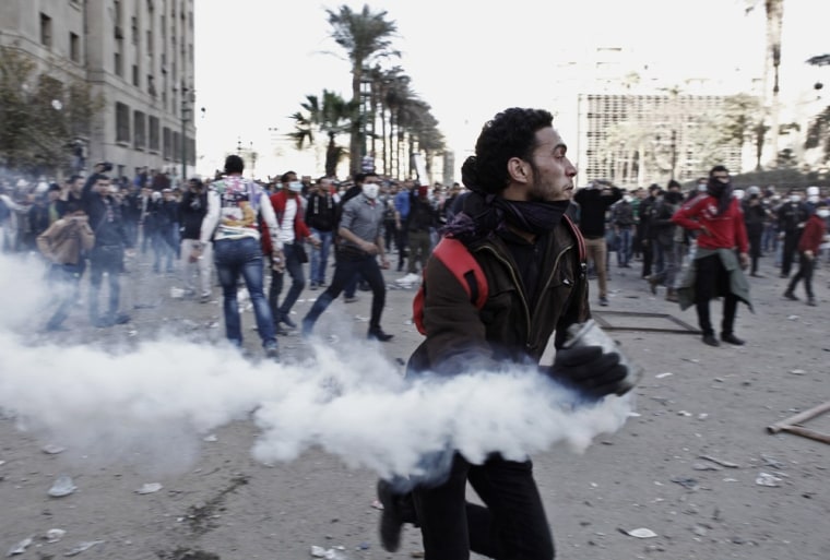 An Egyptian protester runs with a live tear gas canister during clashes with riot police around Cairo's Tahrir Square on Friday.