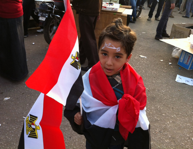 A boy is draped in the Egyptian flag as protesters gather in Tahrir Square in Cairo on Friday. Despite clashes around the square, the atmosphere inside was festive at times.