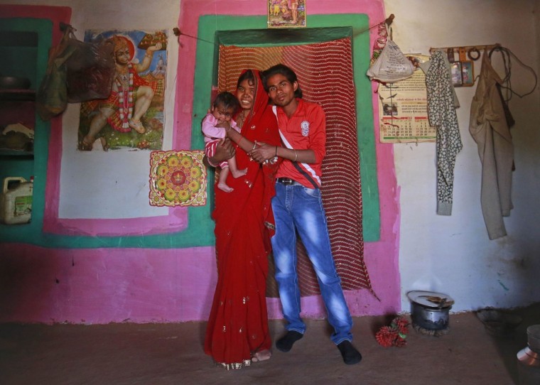 Jan. 21, 2013: Krishna, 14, poses with her four-month-old baby Alok and husband Kishan Gopal, 16, inside the living room of their house in a village near Baran, Rajasthan.
