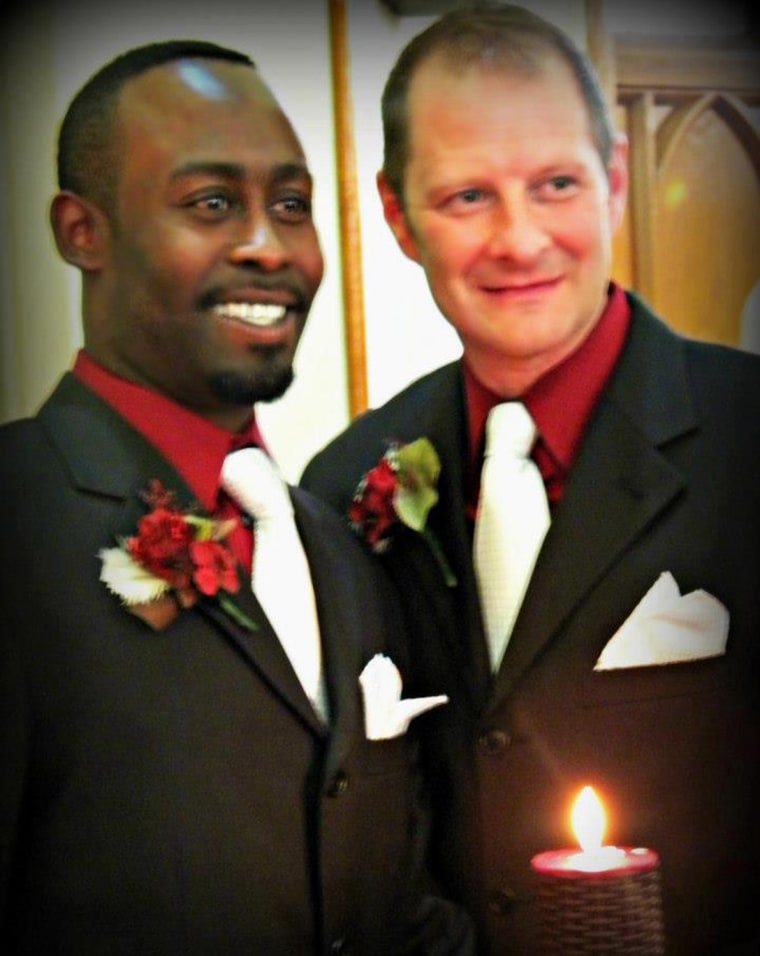 Bishop Erik Swope-Wise, right, and his husband Kelsey Swope-Wise stand before a unity candle on their wedding day on April 28, 2012. The photo was inadvertently removed from Facebook by the site after a complaint was made about the image.