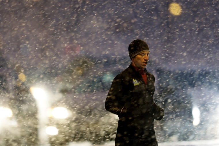 A runner passes crosses a street during a winter snow storm, Friday, in Philadelphia.