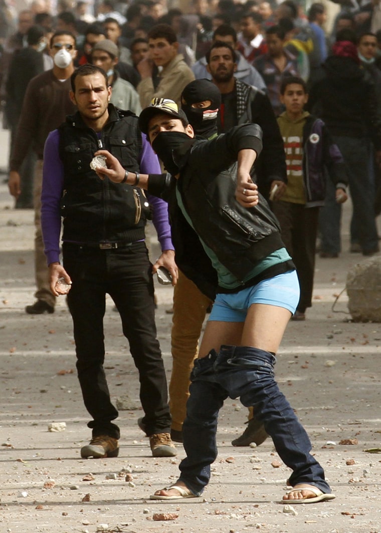 With his trousers around his knees to show defiance, a protester throws stones towards riot policemen and other demonstrators who have taken the side of security forces during clashes near Cairo's Tahrir Square on Jan. 27, 2013.
