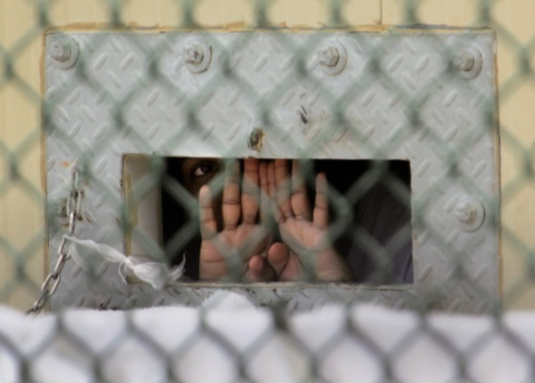In this photo, reviewed by a U.S. Dept of Defense official, a detainee shields his face as he peers out through the so-called