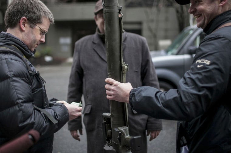 Mason Vranish, left, pays $100 cash for a used missile launcher outside of a Seattle Police Department gun buyback program in Seattle, Wash., on Jan. 26. Participants received up to a $100 gift card in exchange for working handguns, shotguns and rifles, and up to a $200 gift card for assault weapons. The event lasted from 9 a.m. until shortly after noon, after the event ran out of $80,000 worth of gift cards.