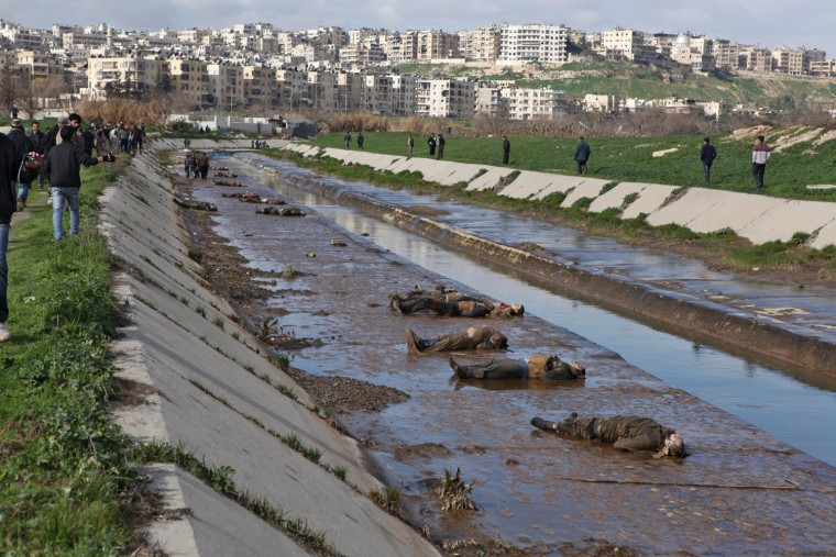 Locals gather at the banks of a small canal containg the bodies of dozens of people on Jan. 29 in Aleppo, Syria.