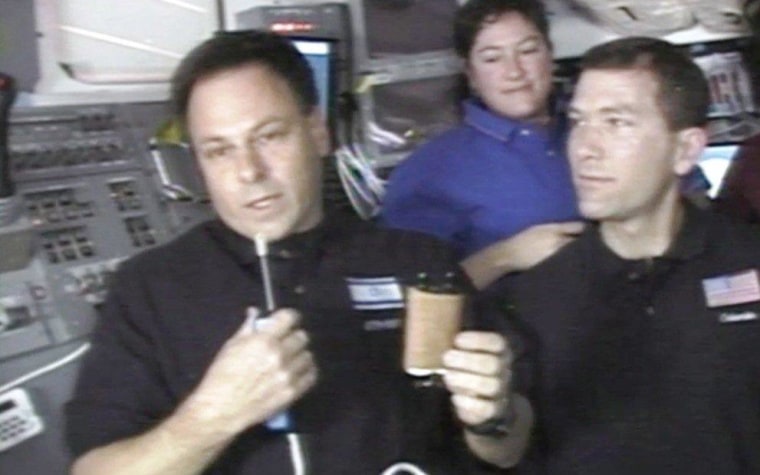 Israeli astronaut Ilan Ramon holds up a miniature Torah scroll during Columbia's final mission in 2003, as fellow astronaut Laurel Clark and mission commander Rick Husband look on.