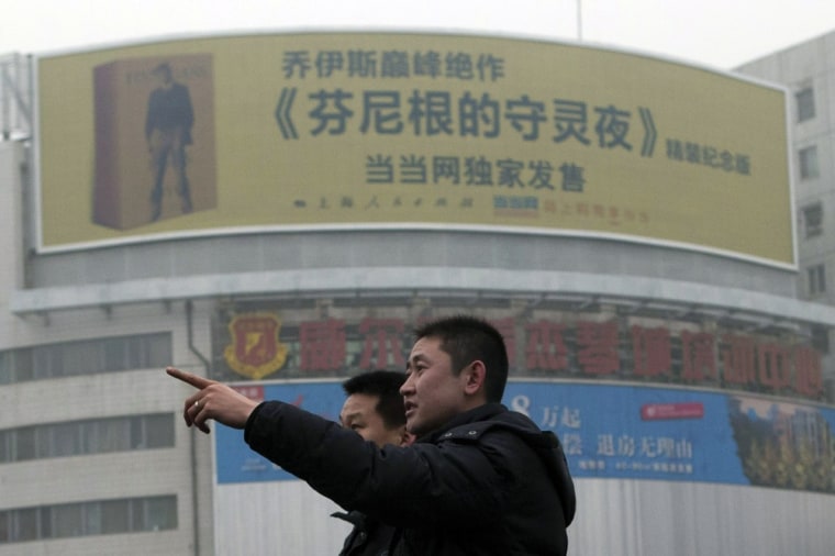 A Chinese man points near a large billboard advertising the translated work of James Joyce's