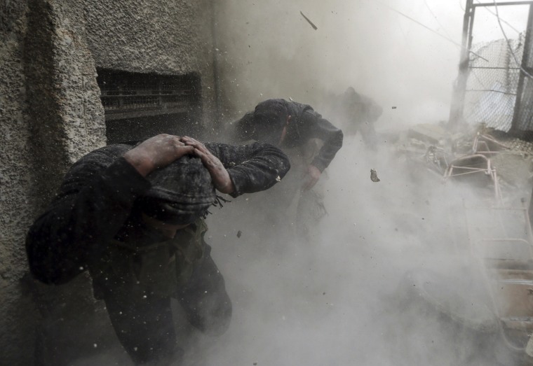 Free Syrian Army fighters run for cover as a tank shell explodes on a wall during heavy fighting in the Ain Tarma neighborhood of Damascus, on Jan. 30.