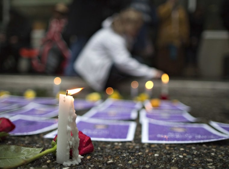 A supporter lights candles surrounding photos of murdered women outside the Missing Women's Commission of Inquiry in Vancouver, British Columbia on Dec. 17.
