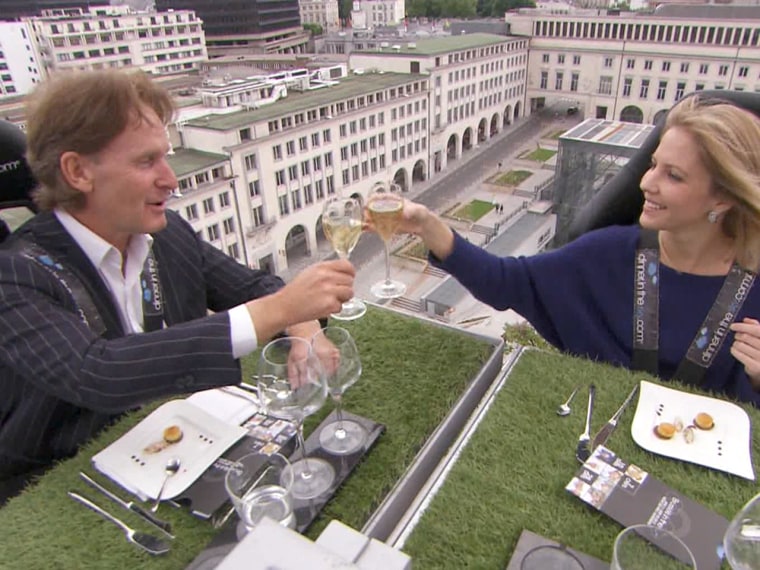 TODAY's Michelle Kosinski toasts a fellow diner while strapped into her seat high above Brussels.