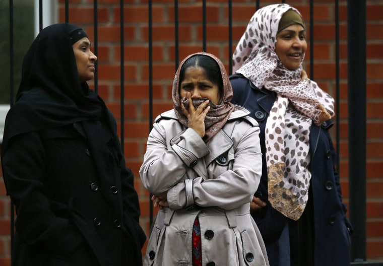 A woman covers her mouth as she looks at a fire at a recycling plant in Smethwick, central England on July 1, 2013.
