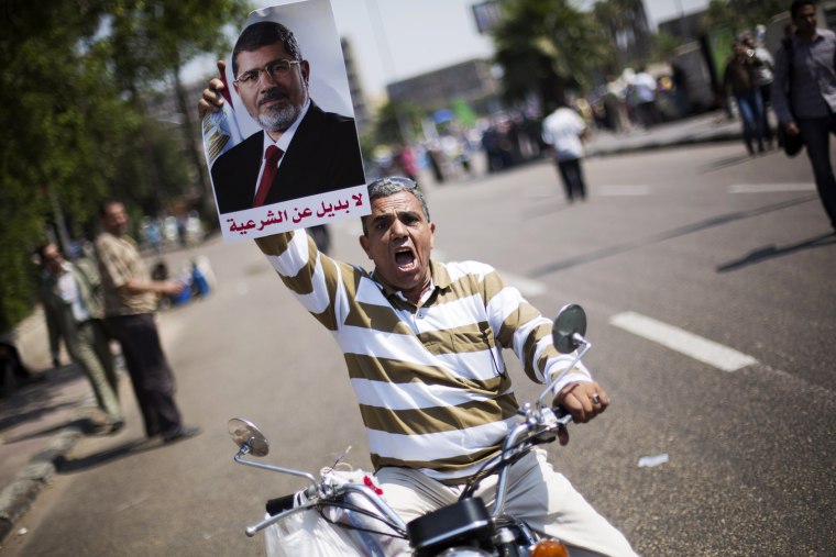 An Egyptian man holds a poster supporting Egypt's Islamist President Mohammed Morsi, with Arabic writing that reads