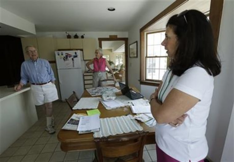 Robert Post, left, and his wife, Jane Post, center, talk to neighbor Gail Kender inside their home, in Mantoloking, N.J. The Posts' home was flooded during Superstorm Sandy, wiping out the phone line. Post has a pacemaker that needs to be checked once a month by phone, but the phone company refuses to restore the area's landlines after they were damaged by the storm.
