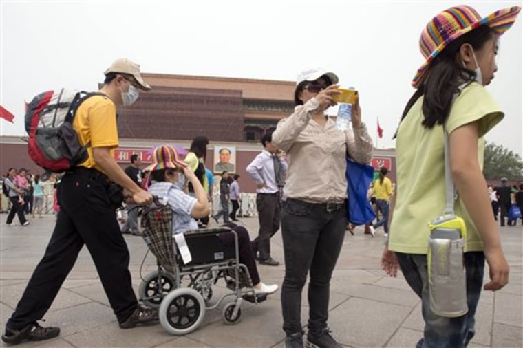 In this Tuesday, May 7, 2013 photo, visitors to Tiananmen Gate wear masks during a day of heavy pollution in Beijing. Air pollution significantly shor...