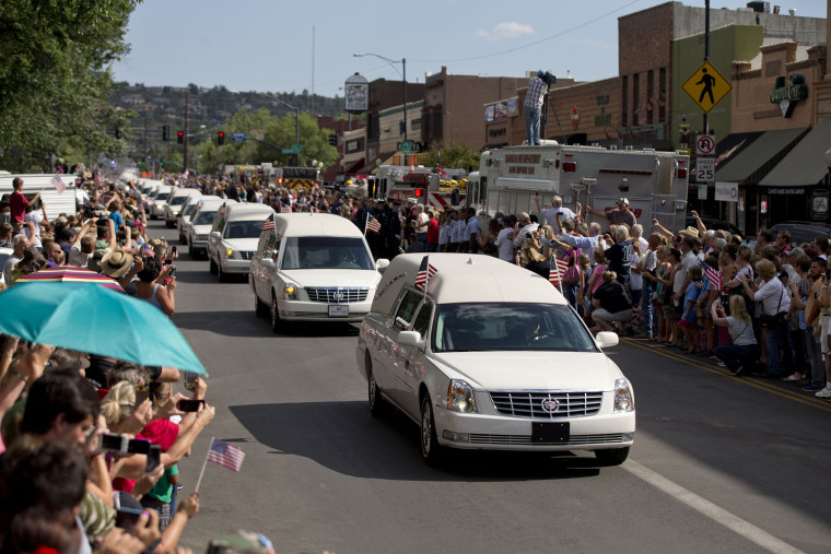 Hundreds of people line Montezuma Street Sunday, July 7, 2013 in downtown Prescott, Ariz. to pay respects as 19 hearses slowly roll by carrying the 19 Granite Mountain Hotshot firefighters killed a week ago by an out-of-control blaze near Yarnell, Ariz. The nearly five-hour-long procession began near the state Capitol in Phoenix, went through the town where the Granite Mountain Hotshots were killed and ended in the mountain community of Prescott, where they lived and will be laid to rest this week. (AP Photo/Julie Jacobson)