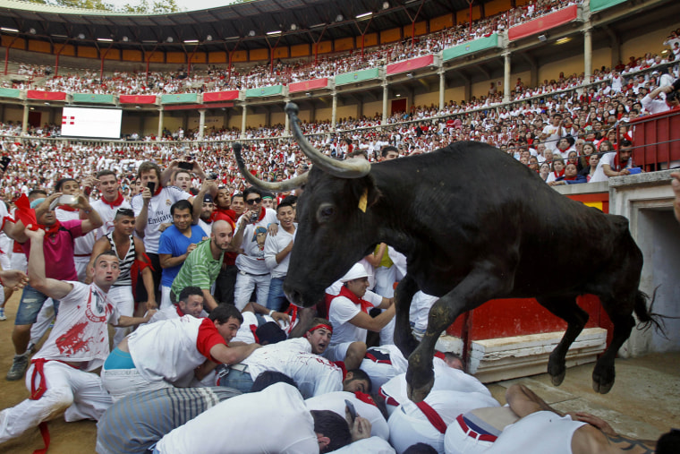 A cow jumps over revelers lying down on the bull ring at the end of the fifth run of the famed San Fermin festival in Pamplona, Spain, on July 11.