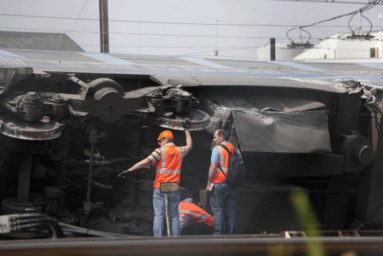 Railway's employees are seen on the scene where a train derailed at a station in Bretigny sur Orge, south of Paris, Saturday, July 13, 2013.