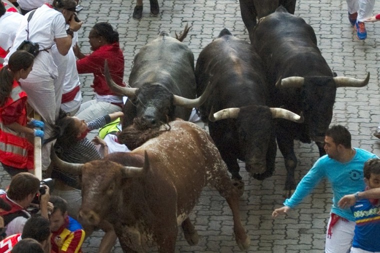 An unidentified 23-year-old Australian woman, wearing a white t-shirt, falls in between bulls after being gored by a Miura fighting bull in Spain,