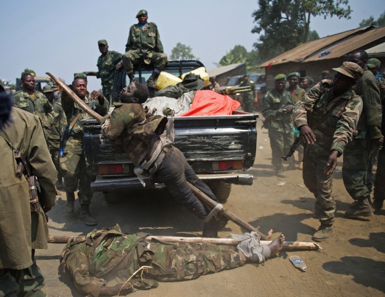 The bodies of two alleged M23 fighters are dumped out of the back of a pickup truck by Congolese Army soldiers in the village of Rusayo on July 16, 2013 during a press visit. According to the army, one of the men was Ugandan and the other Rwandan, but they could not produce the identity cards that they claimed to have seen proving this.