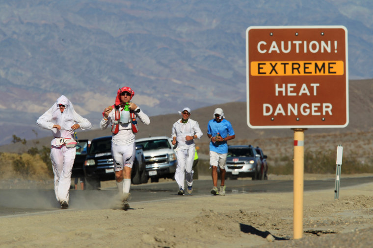Runners pass a heat danger warning sign during the AdventurCORPS Badwater 135 ultra-marathon race on July 15, 2013 in Death Valley National Park, Calif.