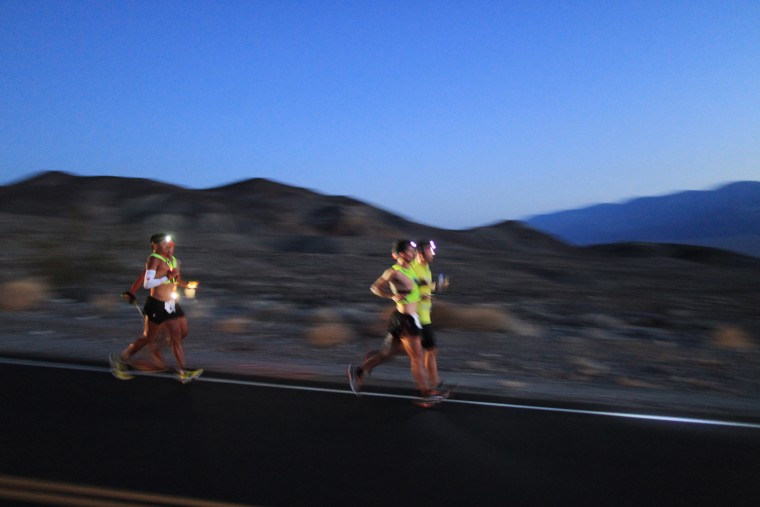 Oswaldo Lopez (near L) of Madera, California and Carlos Alberto of Portugal (near R) run wearing headlamp near Panamint Springs as night falls during the AdventurCORPS Badwater 135 ultra-marathon race on July 15, 2013 in Death Valley National Park, Calif.