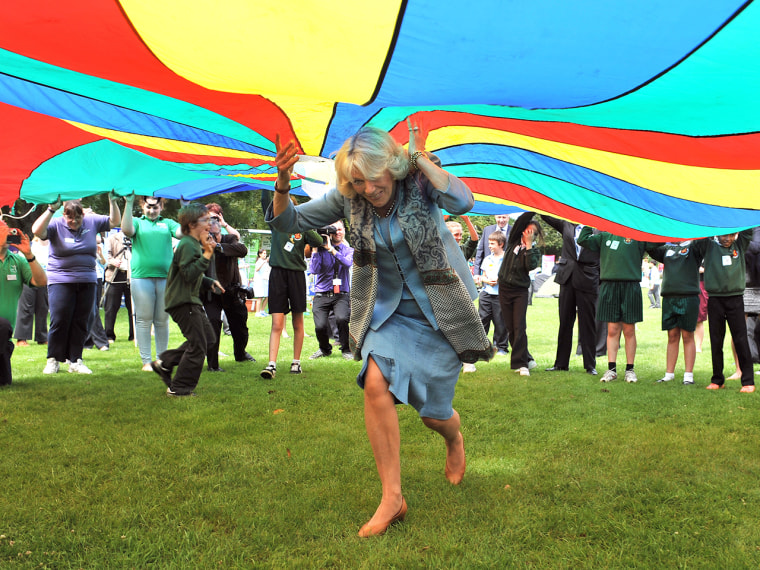 Image: Camilla runs under a brightly colored parachute during a youth rally on July 19, 2012 in Guernsey during a Diamond Jubilee visit to the Channel Islands with Prince Charles.