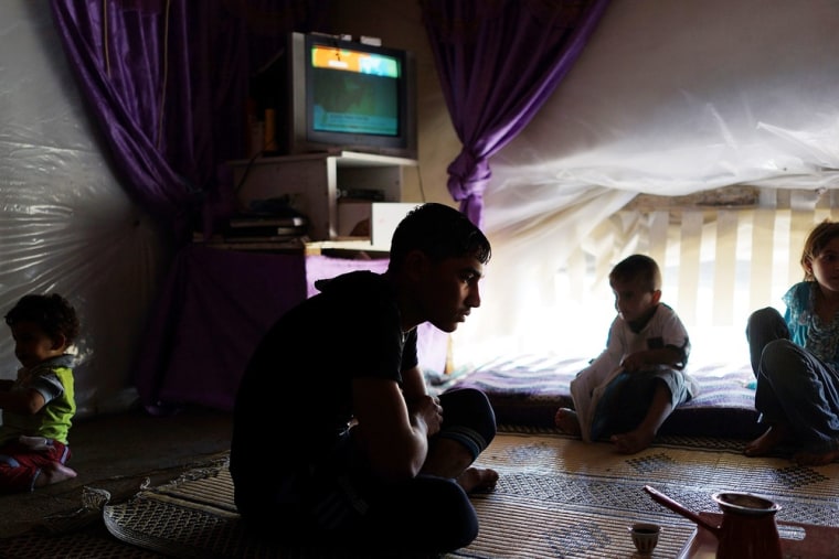 A family from the city of Homs watches television in their tent inside a camp for Syrians who have fled the fighting in their country on June 28, 2013 in Baalbek, Lebanon.