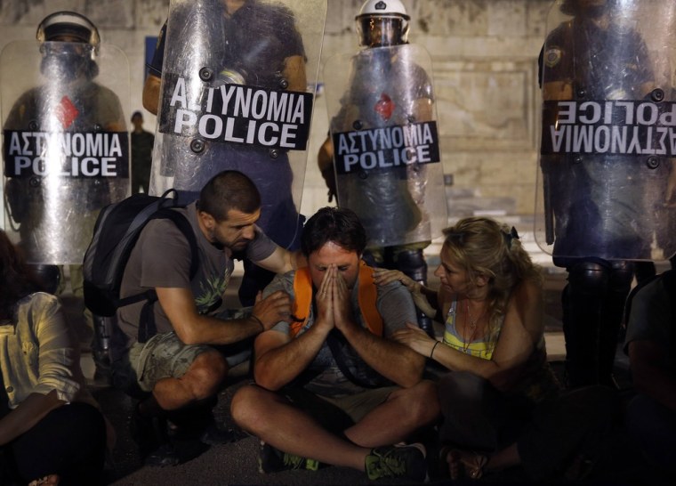 Municipal public school guard Yiorgos Avramidis, 43, is comforted by colleagues in front of a police line guarding the Greek parliament in Athens, late July 17, 2013, as lawmakers vote on a bill to sack public sector workers. Avramidis, who is married with two children of three and six, is one of more than 2,000 public school guards who will lose their jobs.