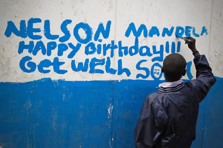 A boy paints a message for former South African President Nelson Mandela on the wall at Kilimani Primary School in Nairobi, Kenya.