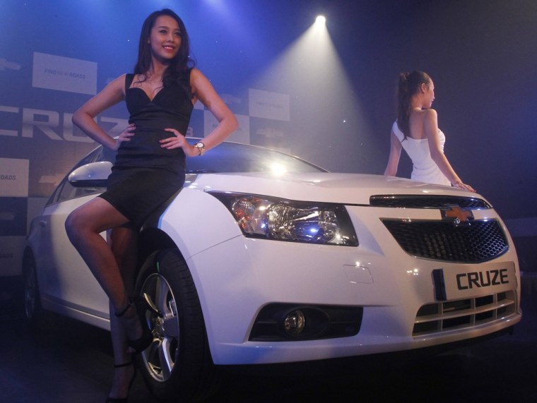 Models pose next to the new Chevrolet Cruze car of the 2013 series, during its launching ceremony in Hanoi in June. The launch of the next generation ...
