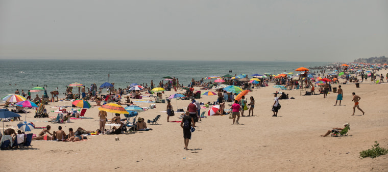 People flock to Rockaway Beach during a heat wave on July 17, 2013.