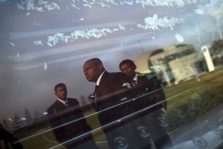Pallbearers Hertor Fano, center, Victor Rivas, right, and Victor's nephew Alex Rivas, are reflected in the window of a hearse as they work at a funeral in Lima on May 11, 2013.