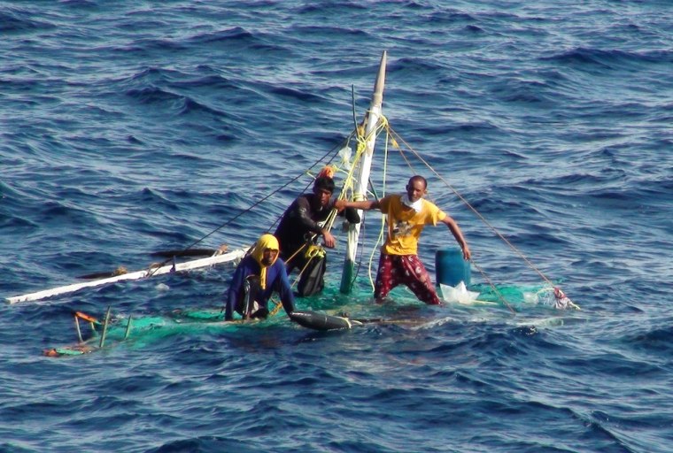 Three Filipino fishermen hold on to their waterlogged boat as they await rescue off the south of Taiwan, in a photo released on July 22, 2013.