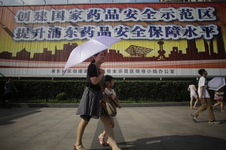 Tourists walk in front of a public service advertisement of drug safety in Shanghai, China, Monday, July 22, 2013.
