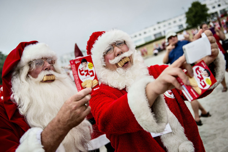 Two Santas photograph themselves with their mouths full of biscuits during the annual Santa Claus World Congress in Denmark.