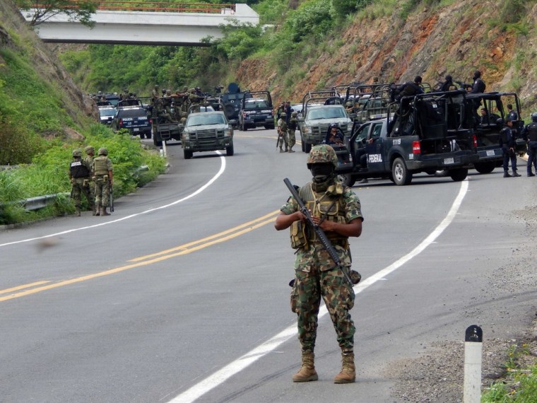 Federal agents and soldiers of the Mexican Army stand guard on a road where alleged drug traffickers attacked federal policemen, leaving at least 20 criminals and two federal agents dead, near Arteag in the state of Michoacan, Mexico, on Tuesday.