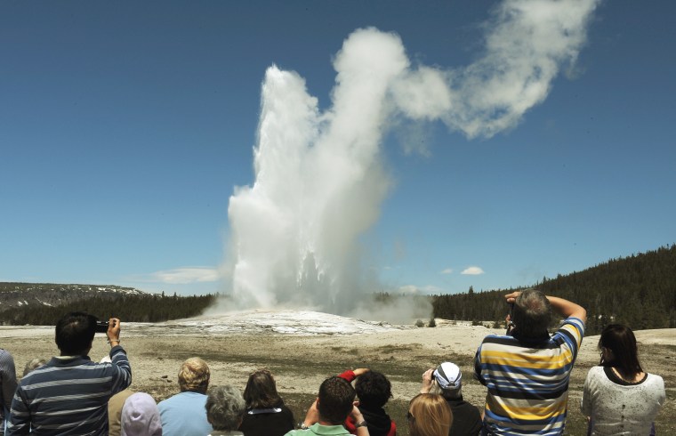 Tourists watch the 'Old Faithful' geyser which erupts on average every 90 minutes in the Yellowstone National Park, Wyoming on June 1, 2011.  Yellowst...