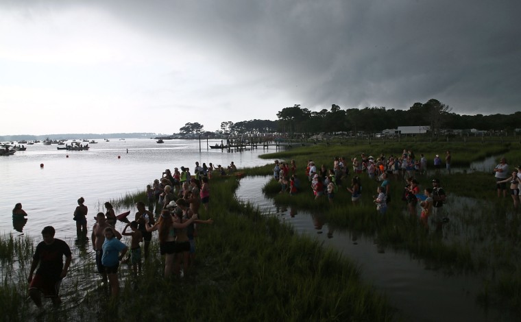 People wait for the wild ponies in the marsh as a storm approaches in Chincoteague, Va., on July 24, 2013.
