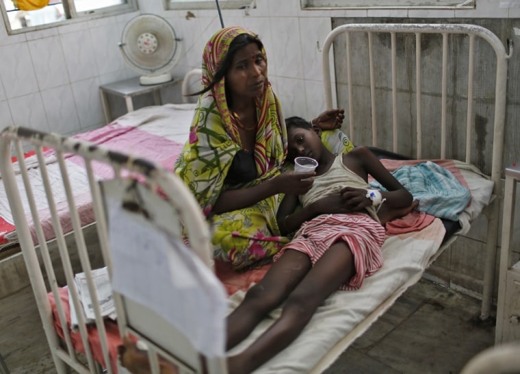 A sick boy lies on his mother's lap inside a hospital after he consumed contaminated meals given to children at a school on Tuesday, in the eastern Indian city of Patna July 18, 2013.