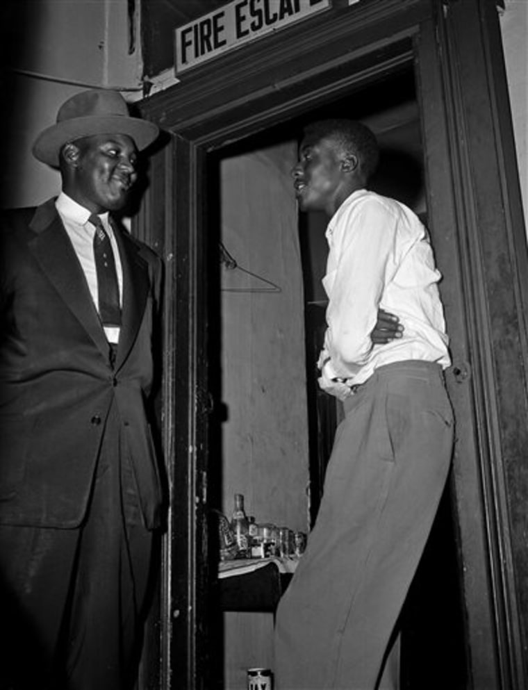 In this Sept. 29, 1955 photo, Willie Reed, right, a witness in the Emmett Till murder case in Mississippi, stands outside the door of his apartment in Chicago under guard by Detective Sherman Smith.