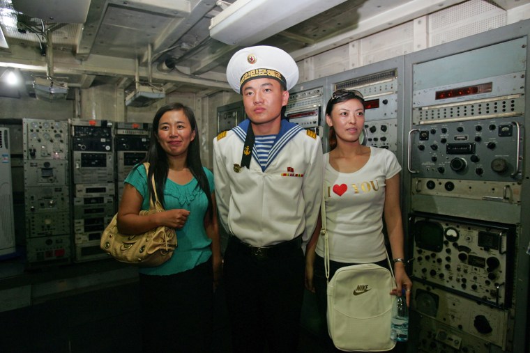 A North Korean sailor poses for a picture with Chinese tourists aboard the USS Pueblo, docked in Pyongyang, in 2007.