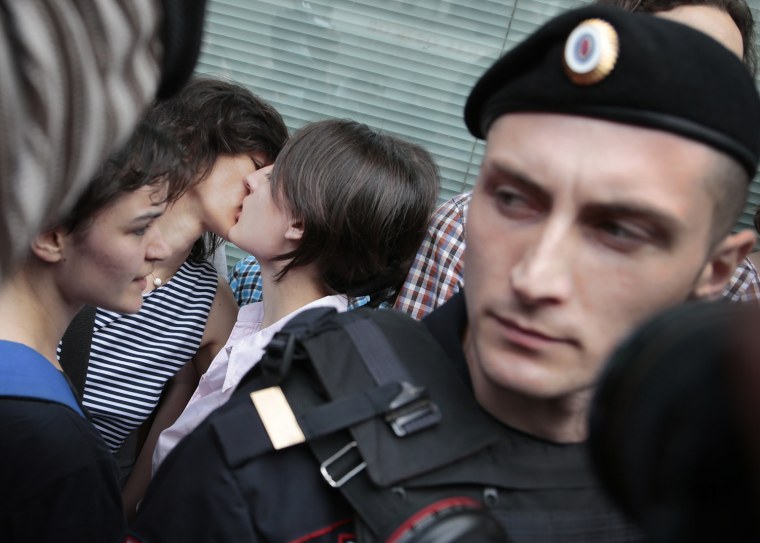 Police officers watch gay rights activists kiss near the State Duma, Russia's lower parliament chamber, in Moscow, Russia, on June 11, 2013. Protesters attempted to rally outside the Russian State Duma before a final vote on the bill banning