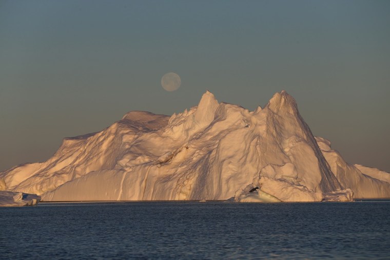 A full moon is seen over an iceberg that broke off from the Jakobshavn Glacier on July 23 in Ilulissat, Greenland.